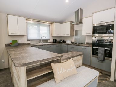A kitchen with an L-shaped countertop cabinets a sink oven and microwave at Parkers Place in Carnforth