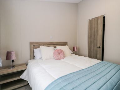 A bedroom with a bed with white bedding and blue throw and bedside tables with lamps at Parkers Place in Carnforth