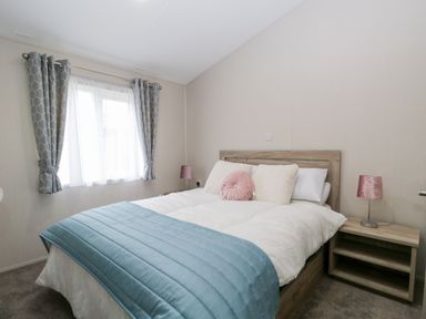 A bedroom with a bed with white and blue bedding and a nightstand with a lamp at Parkers Place in Carnforth