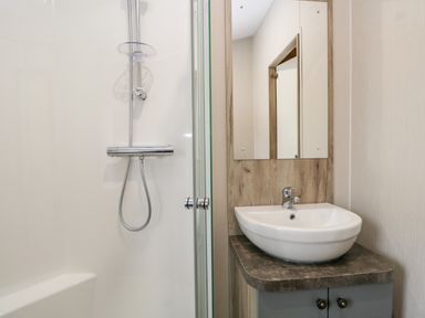 A bathroom with a shower and a sink with a mirror above at Parkers Place in Carnforth