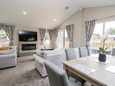 A living room with a television above a fireplace sofas and a dining table with chairs at Parkers Place in Carnforth