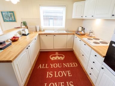 A kitchen with white cabinets wooden countertops a red rug with text a window and various kitchen appliances at Tanqueray Lodge in Kenwick near Louth