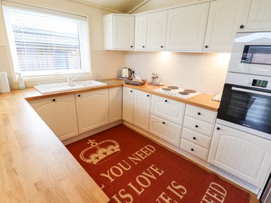 A kitchen with white cabinets wooden countertops a stove and oven and a rug with a crown at Tanqueray Lodge Kenwick near Louth