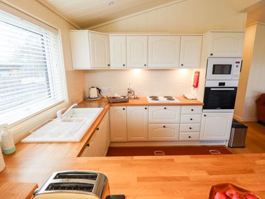 A kitchen with white cabinets wooden countertops a toaster and a window at Tanqueray Lodge Kenwick near Louth