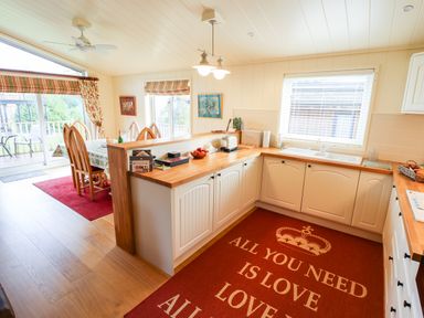A kitchen with wooden countertops and white cabinets connected to a dining area with wooden chairs and a table at Tanqueray Lodge in Kenwick near Louth