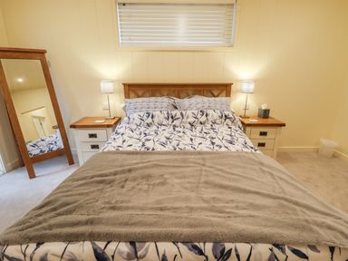 A bedroom with a bed between two nightstands with lamps and a mirror on the left side at Tanqueray Lodge Kenwick near Louth