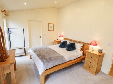 A bedroom with a wooden bed and bedside tables with lamps at Tanqueray Lodge Kenwick near Louth