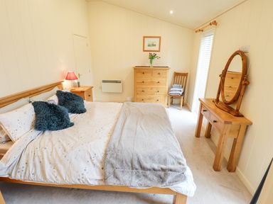 A bedroom with a bed a dresser a chair and a dressing table at Tanqueray Lodge in Kenwick near Louth