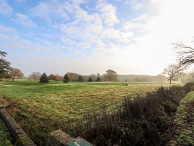An open grassy landscape with scattered trees under a partly cloudy sky at Tanqueray Lodge in Kenwick near Louth