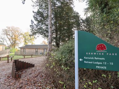 A sign for Kenwick Park retreat lodges next to trees and wooden retreat buildings at Tanqueray Lodge in Kenwick near Louth