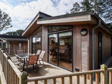 Exterior of a wooden cabin with a deck and outdoor table and chairs at Tanqueray Lodge in Kenwick near Louth