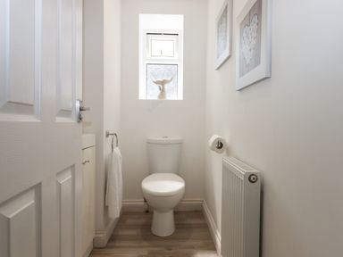 A small bathroom with a toilet a radiator and a window with a decorative object at Apartment at Morningside Hotel Torquay