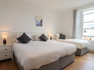 A bedroom with two beds with gray pillows and bedside tables with lamps at Apartment at Morningside Hotel in Torquay