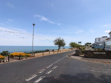 A road with a street sign and lamp posts next to a sea view at Apartment at Morningside Hotel in Torquay