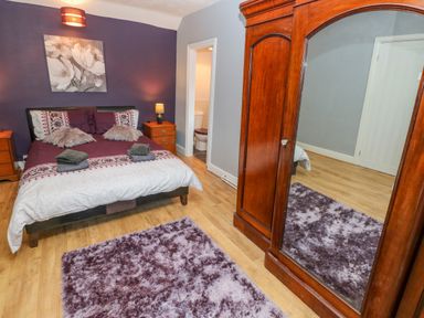 A bedroom with double bed wooden nightstands large wooden wardrobe with mirror and a purple rug at Pant Teg Farm in Carmarthen