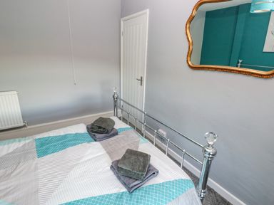 A bedroom with a metal bed frame gray and blue bedding and folded towels on the bed at Pant Teg Farm in Carmarthen