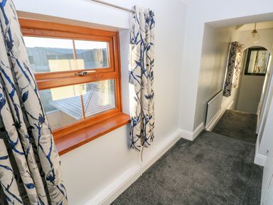 A hallway with a window with curtains and a radiator at Pant Teg Farm in Carmarthen