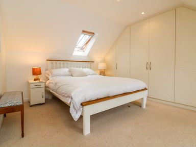 A bedroom with a bed a nightstand lamps bench and built in wardrobes at Barleside in Dulverton