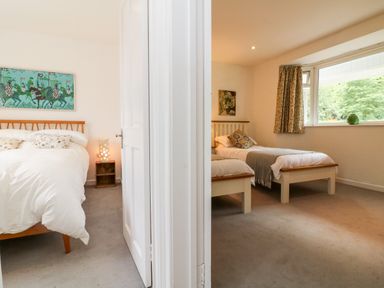 Two bedrooms separated by a door one with a double bed and the other with two single beds at Barleside in Dulverton