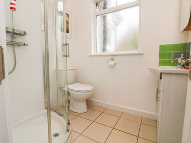 A bathroom with a corner shower, toilet, sink, and frosted window at Barleside in Dulverton