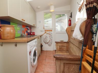 A utility room with a washing machine and wooden bench at Barleside in Dulverton