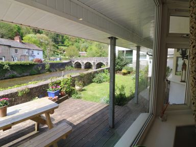 A riverside garden with a wooden bench and picnic table on a deck at Barleside in Dulverton