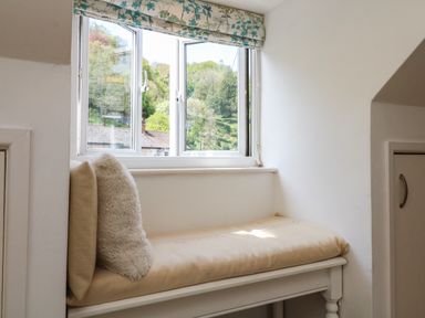 A window seat with beige cushions and a floral valance over the window at Barleside in Dulverton