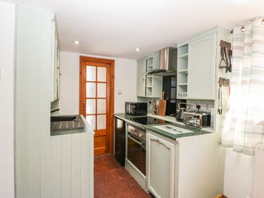 A kitchen with green countertops wooden door and striped curtains at Steel Works Farm in Gorsley