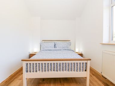 A bedroom with a bed with blue patterned bedding and two bedside tables with lamps at Steel Works Farm in Gorsley