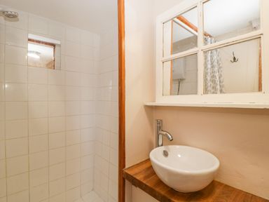 A bathroom with a tiled shower area sink with faucet and a window mirror at Steel Works Farm in Gorsley