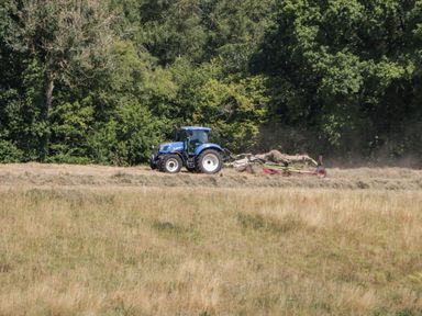 A tractor working on a field with trees in the background at Steel Works Farm in Gorsley