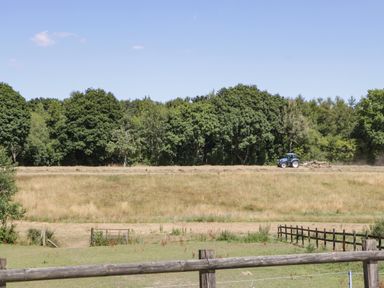 A tractor working on a field with trees in the background at Steel Works Farm in Gorsley