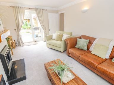 A living room with a green armchair brown leather sofa and wooden coffee table at The Cornerstone in Bourton-On-The-Water