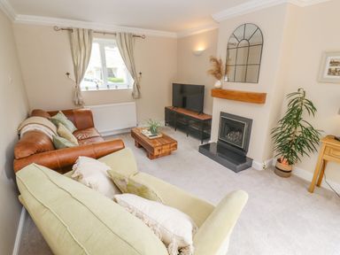 A living room with sofas a coffee table a television a fireplace and a plant at The Cornerstone in Bourton-On-The-Water