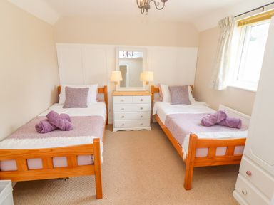 A bedroom with two single beds and bedside table with lamps at The Cornerstone in Bourton-On-The-Water
