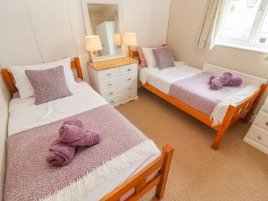 A bedroom with two single beds a dresser with lamps and a mirror at The Cornerstone in Bourton-On-The-Water