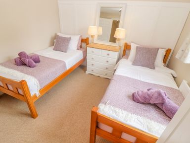 A bedroom with two single beds a white dresser with lamps and a mirror at The Cornerstone in Bourton-On-The-Water