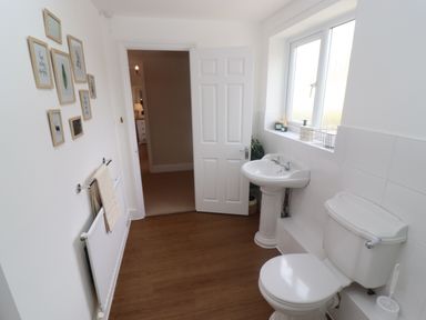 A bathroom with a toilet sink and wall art at The Cornerstone in Bourton-On-The-Water