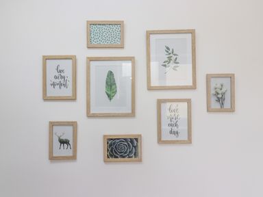 Wall with eight wooden framed pictures featuring plants animals and quotes at The Cornerstone in Bourton-On-The-Water