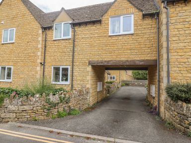 A stone building with a driveway passing underneath at The Cornerstone in Bourton-On-The-Water