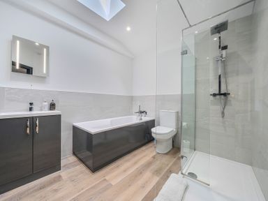 A bathroom with a bath tub, shower, and toilet at The Cottage in Wimborne Minster