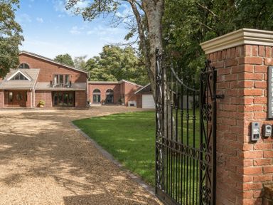 A house with a gravel driveway and gate at The Cottage in Wimborne Minster