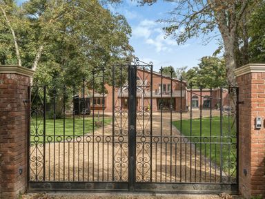 A gated entrance leading to a house and driveway at The Cottage in Wimborne Minster