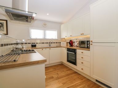 A kitchen with wooden countertops white cabinets a stove oven and a window with blinds at Manor Farm Lodge in Bowerchalke