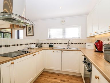 A kitchen with wooden countertops white cabinets a stovetop and sink at Manor Farm Lodge in Bowerchalke