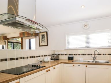 A kitchen with wooden countertops a stove a toaster a teapot a sink and a window with blinds at Manor Farm Lodge in Bowerchalke