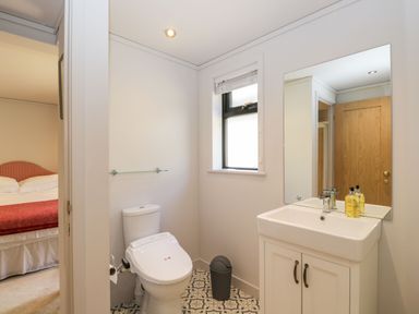 A bathroom with a toilet sink mirror and window next to a bedroom at Manor Farm Lodge in Bowerchalke