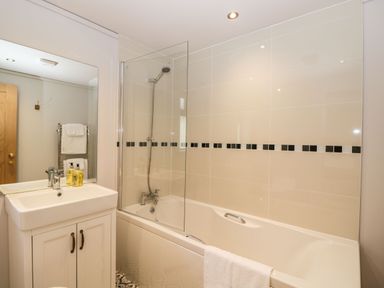 A bathroom with a sink cabinet mirror bathtub and shower at Manor Farm Lodge in Bowerchalke