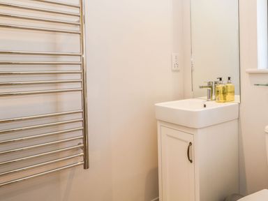 A bathroom sink with a mirror above and a metal towel rack on the wall at Manor Farm Lodge in Bowerchalke