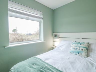 A bedroom with a bed near a window and a pillow with nautical designs at 12 Siesta Mar Mundesley